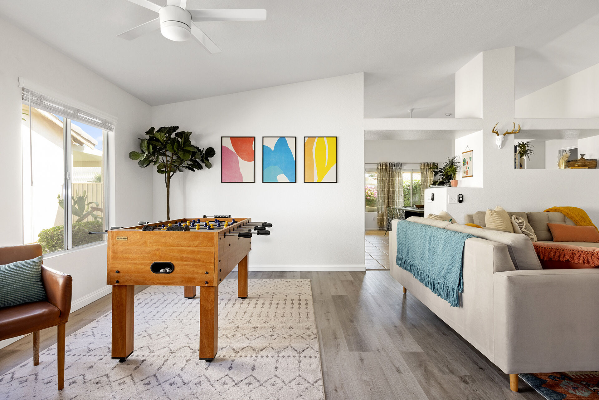 Living room at the Cozy Cactus vacation rental in Indio California with grey sofas, kilim rug, built-in cabinets, and view to kitchen