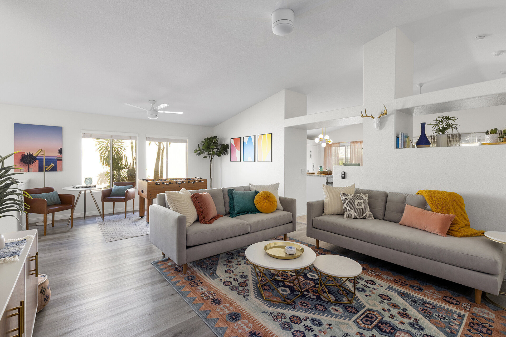 Bright open living room at The Cozy Cactus vacation rental in Indio CA, grey sofas, kilim rug, foosball table, mid-century design