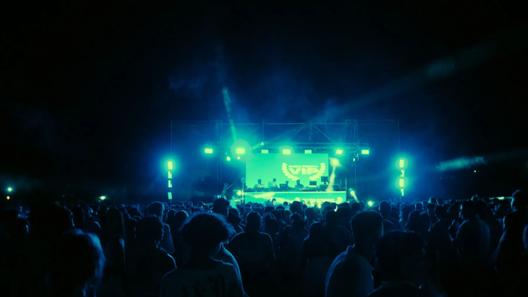 DJ performing on a brightly lit festival stage in front of a large crowd