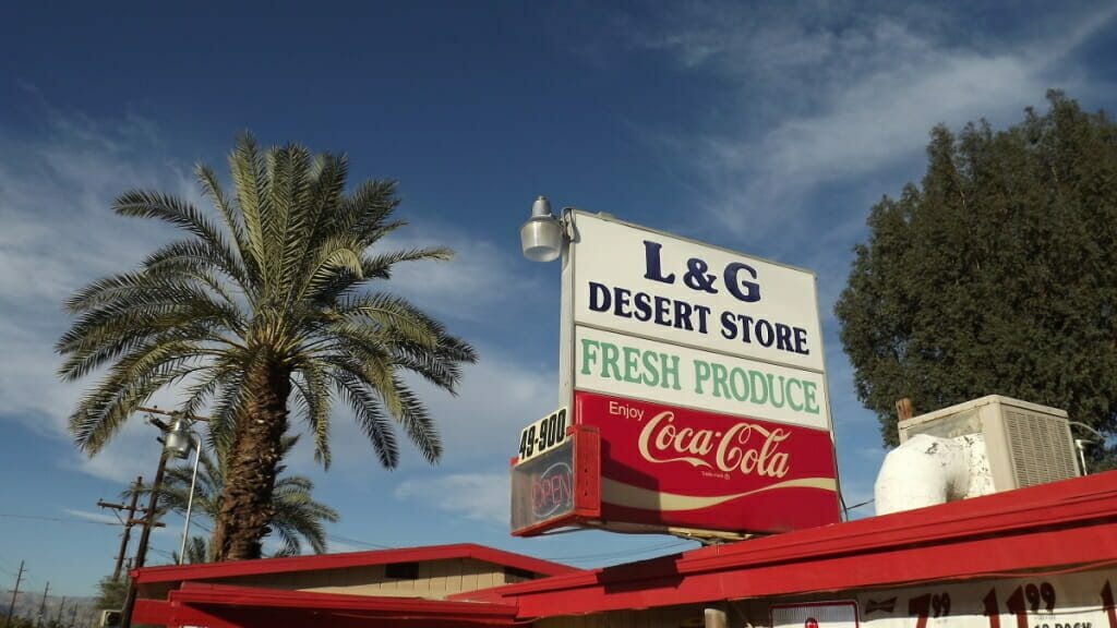 L&G Desert Store roadside sign with Coca-Cola panel and date palm against blue sky, Indio CA