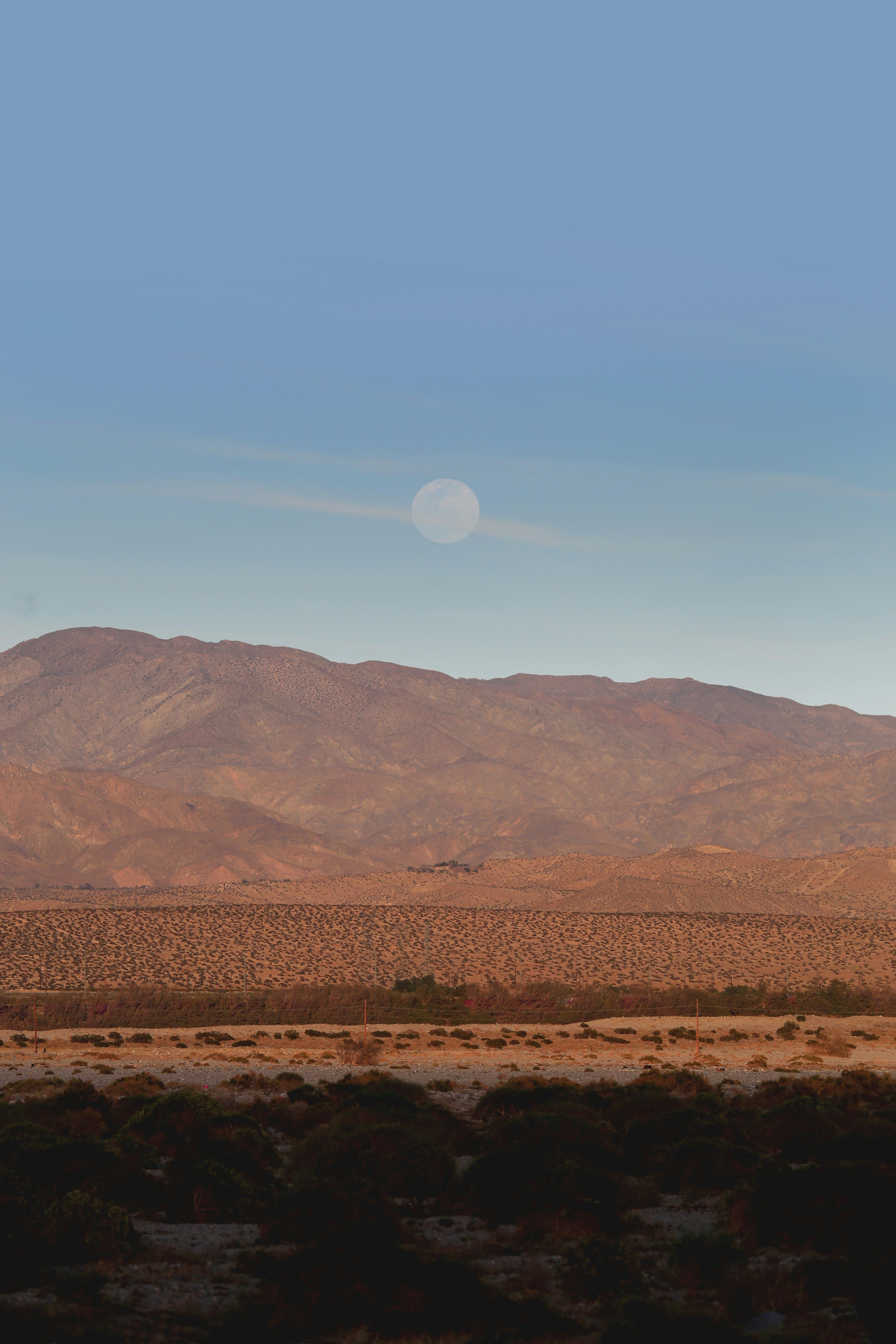 Full moon rising over the desert mountains and Coachella Valley at dusk