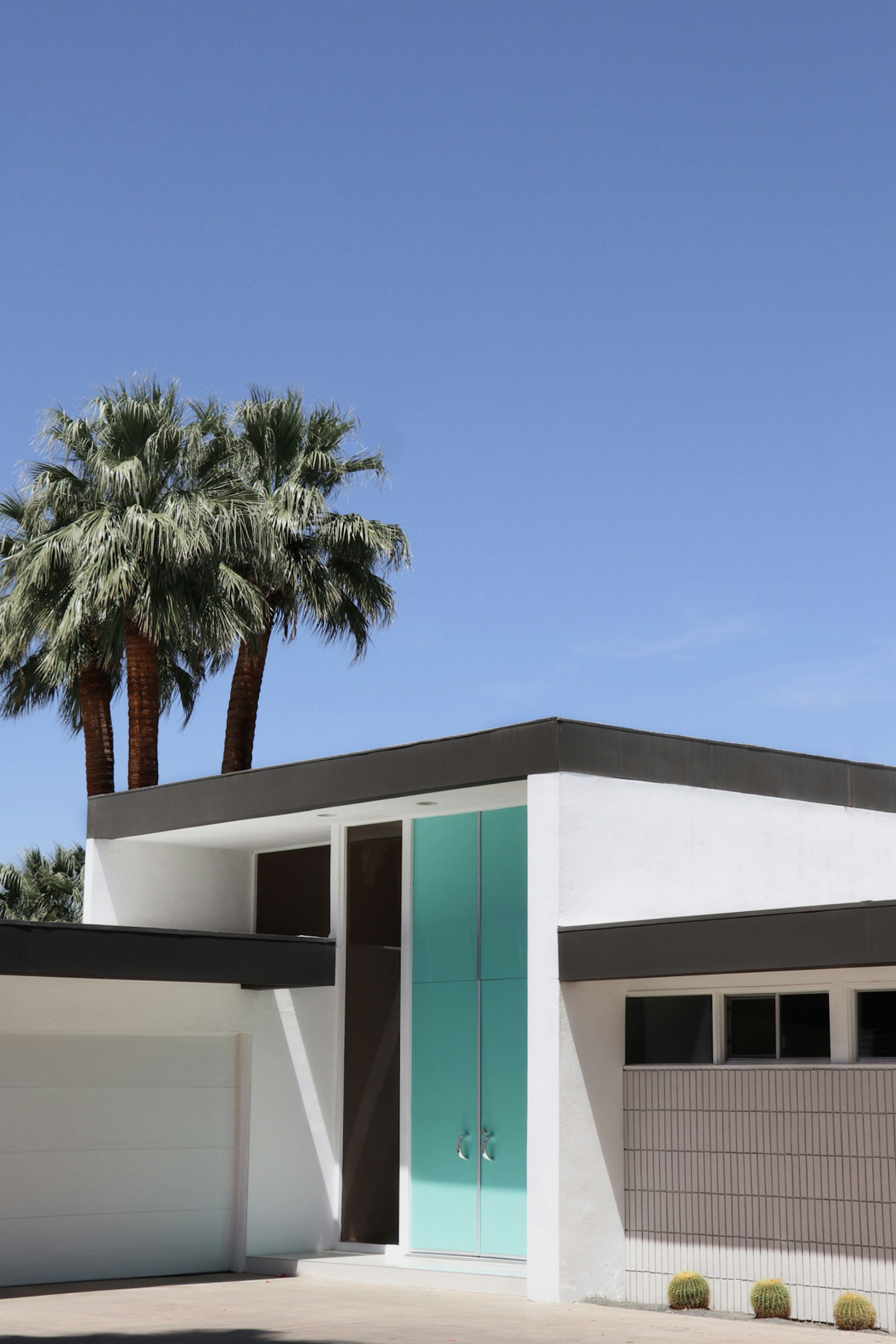 Mid-century modern home with teal door and palm trees in Palm Springs CA