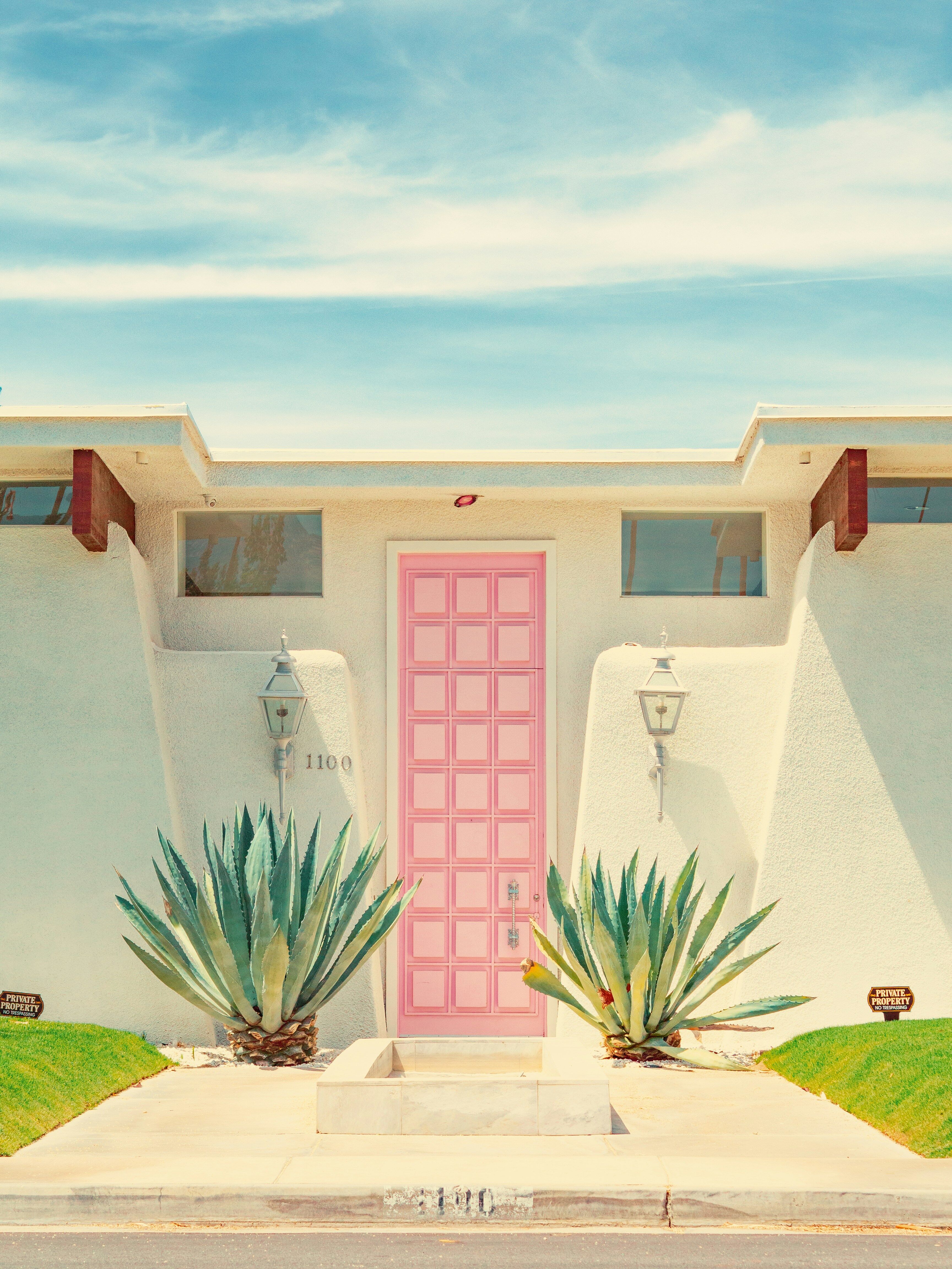 Pink front door on a midcentury modern home in Palm Springs with desert landscaping and mountain backdrop