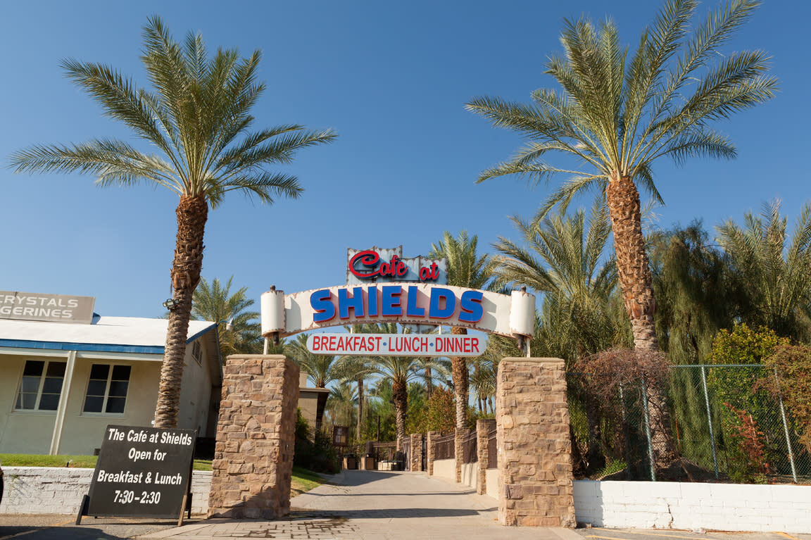 Cafe at Shields Date Garden entrance with neon sign and date palms, Indio CA
