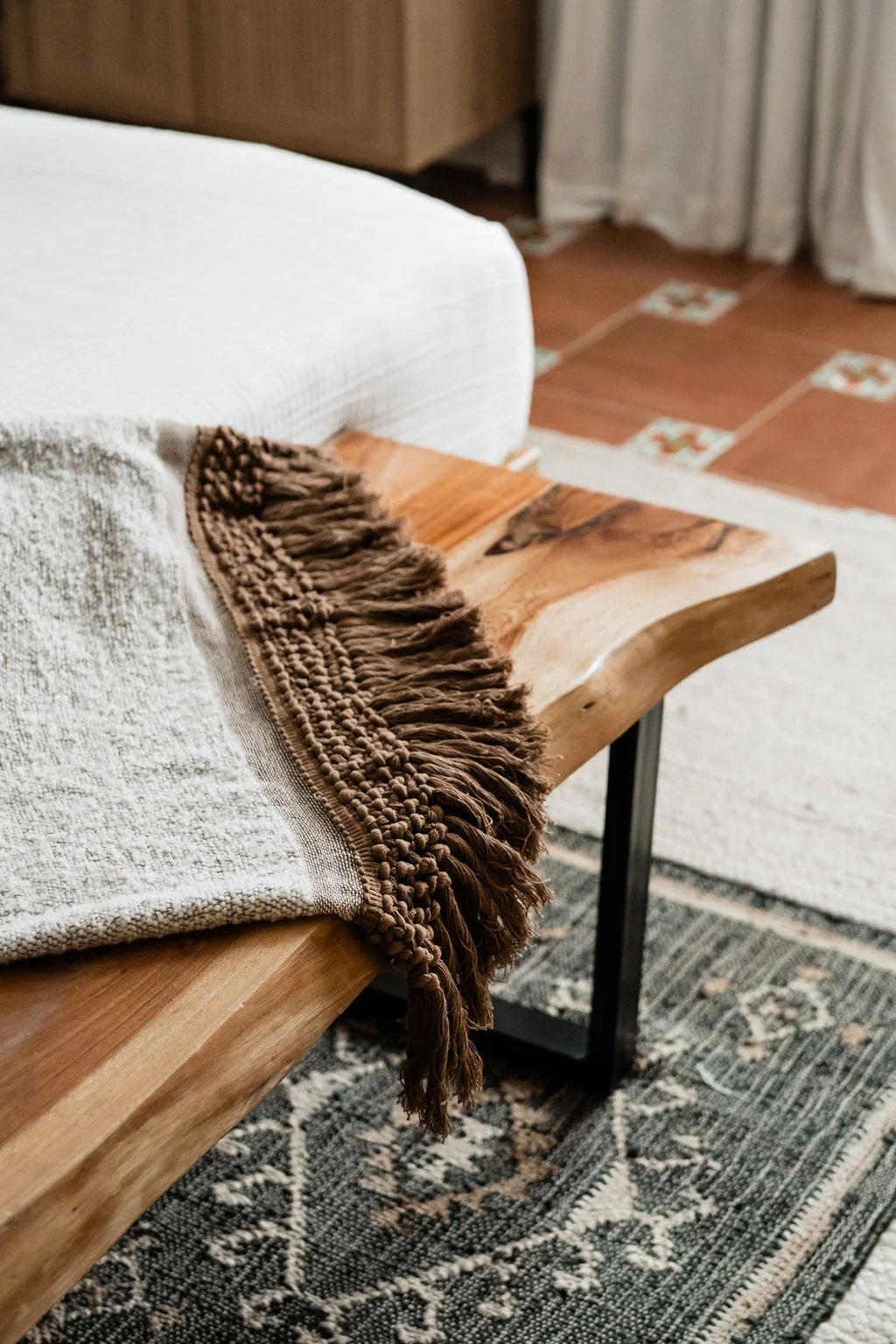Terra Luz primary bedroom live-edge bench with fringed throw and custom LA Tile floor in Indio California