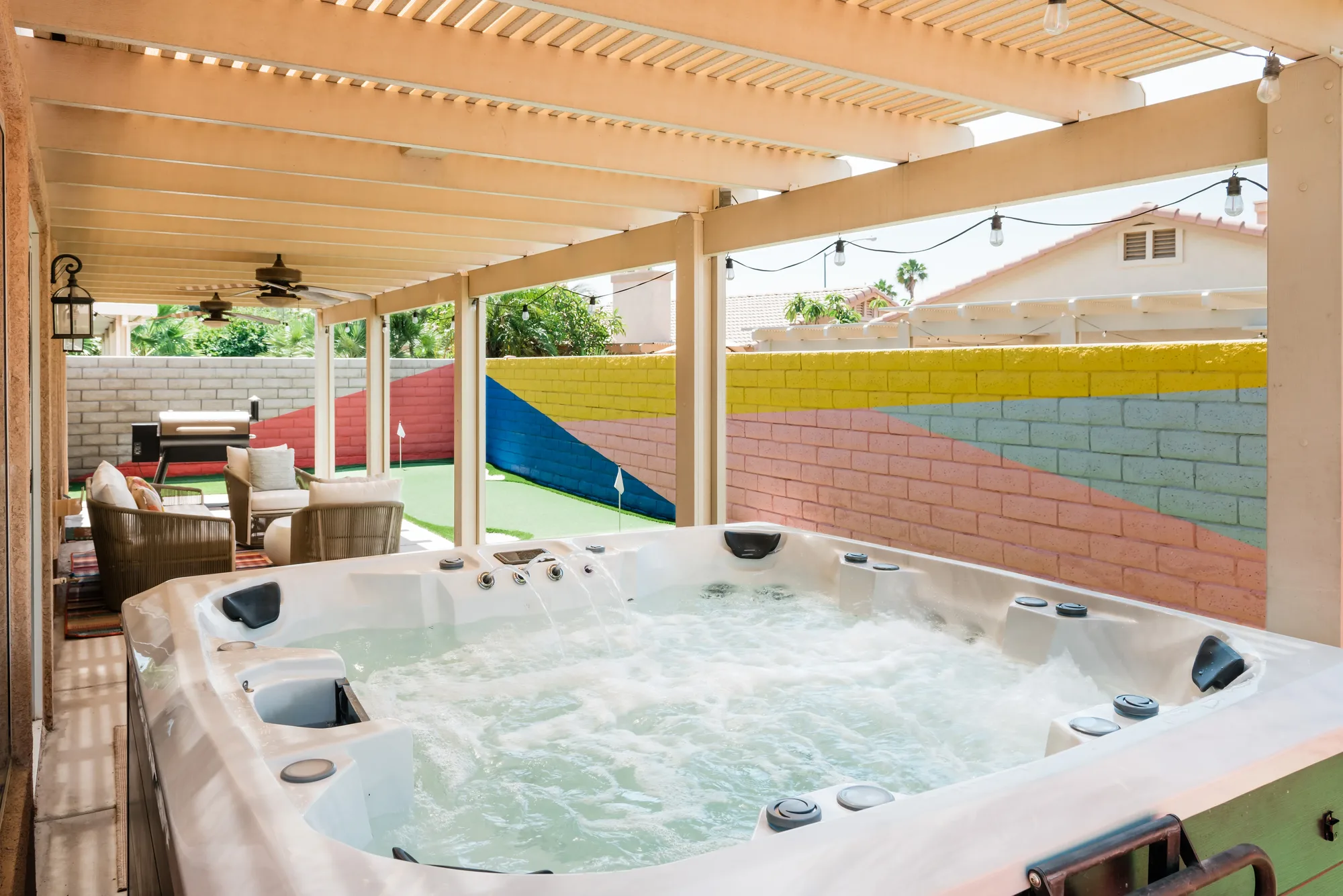 Cozy Cactus backyard overview with pergola, outdoor seating, putting green, and Traeger grill in Indio California