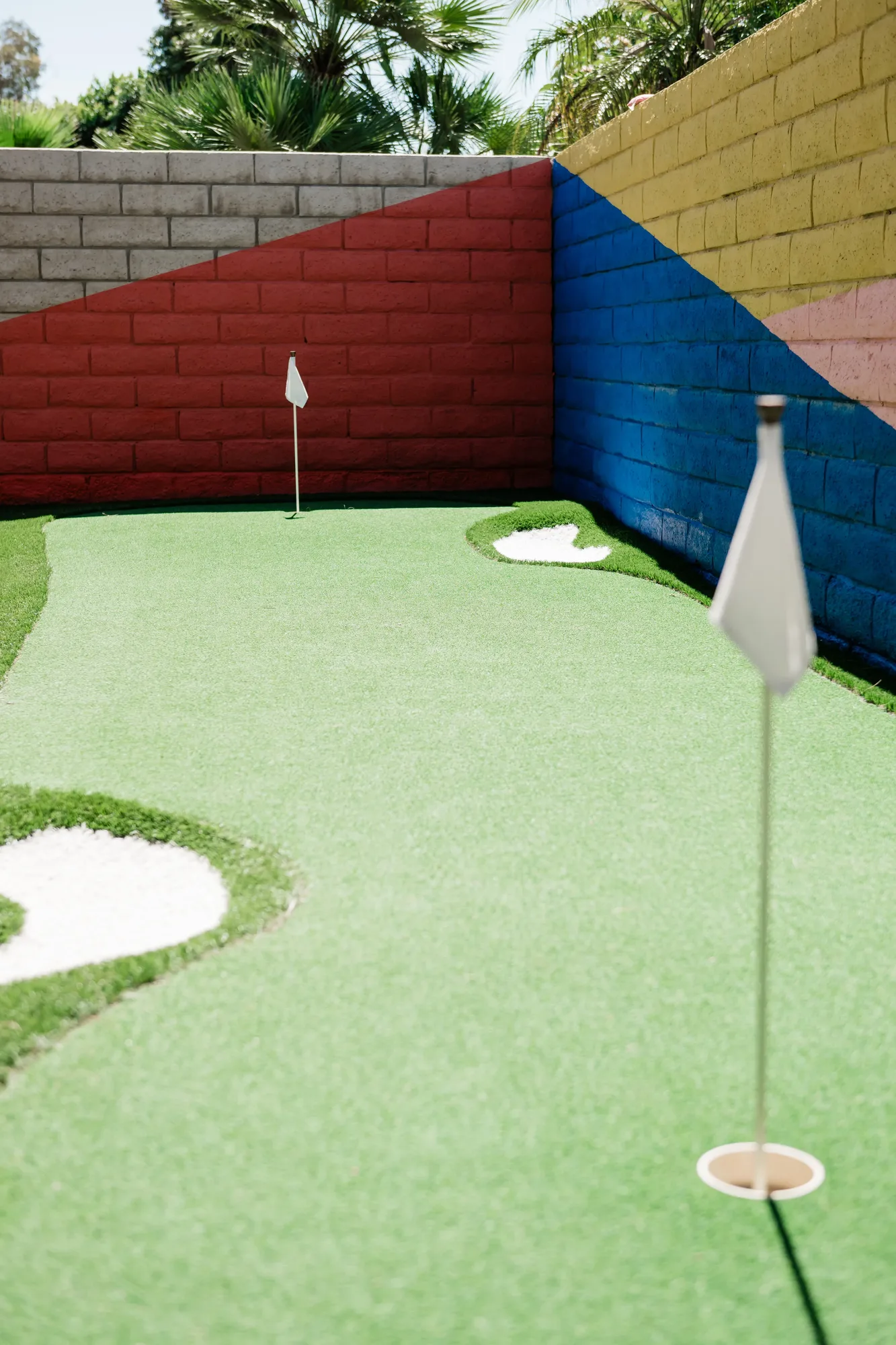 2-hole putting green close-up with flags and colorful painted wall at Cozy Cactus Indio