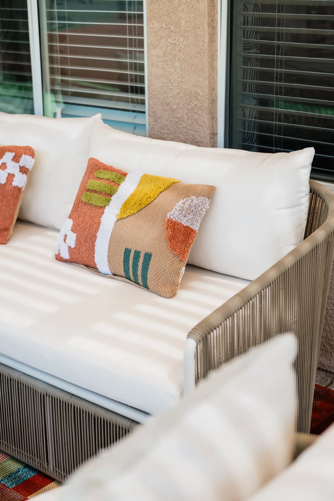 Outdoor rope sofa under pergola with colorful abstract throw pillows at Cozy Cactus