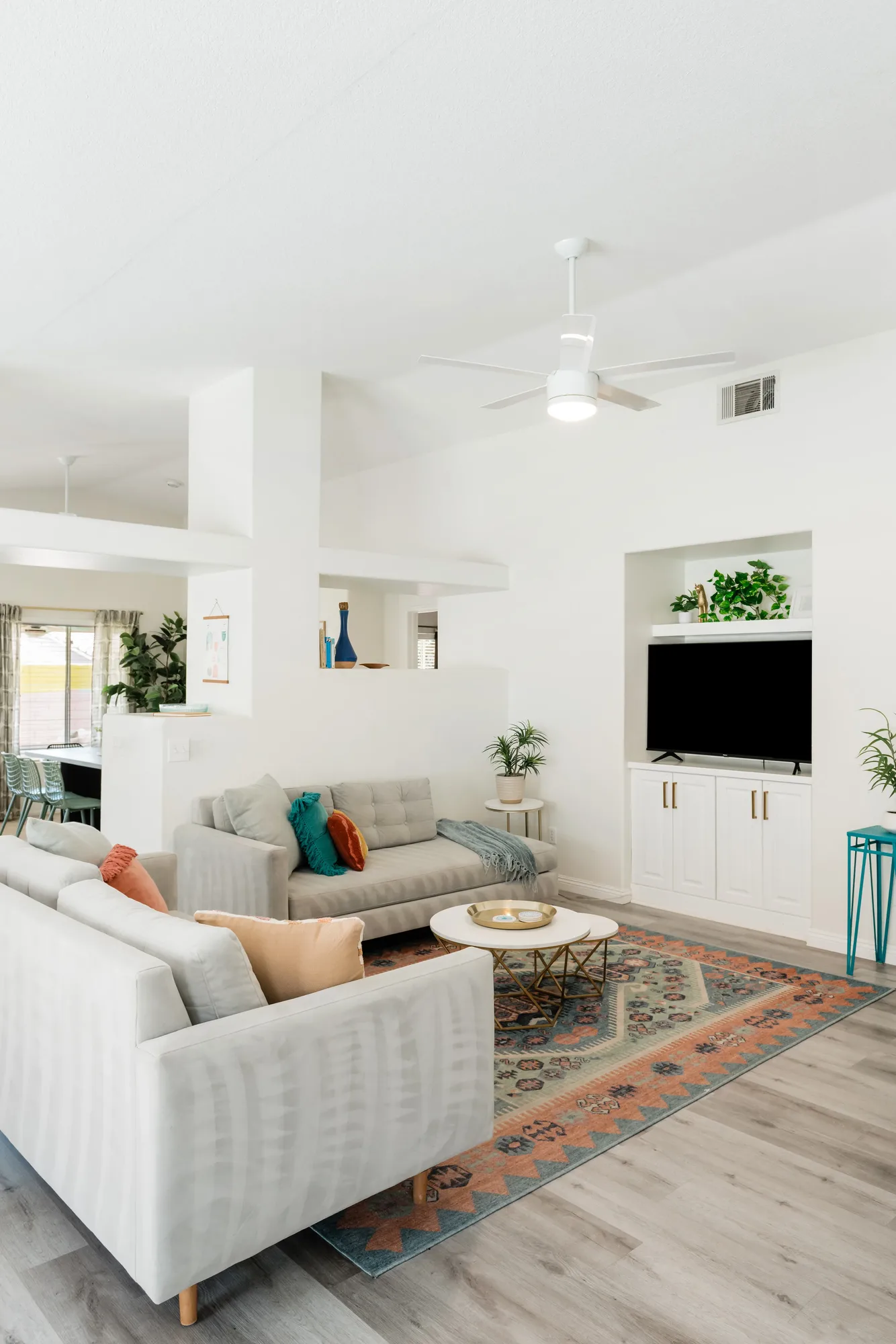 Cozy Cactus open-concept living room with gray linen sofas, kilim rug, built-in TV, and ceiling fan
