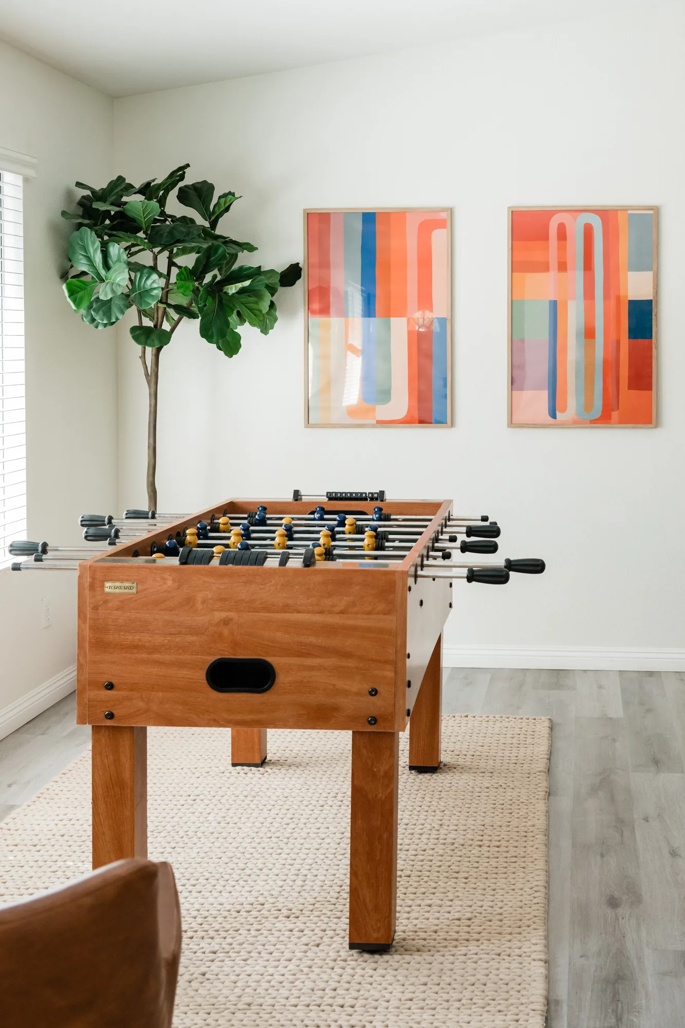 Cozy Cactus game room with foosball table, abstract diptych art, and fiddle leaf tree