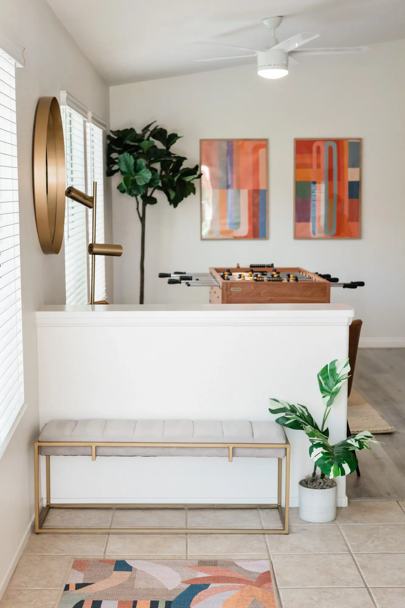 Cozy Cactus entry area with tile-top bench, gold round wall sconce, abstract art, and entry rug