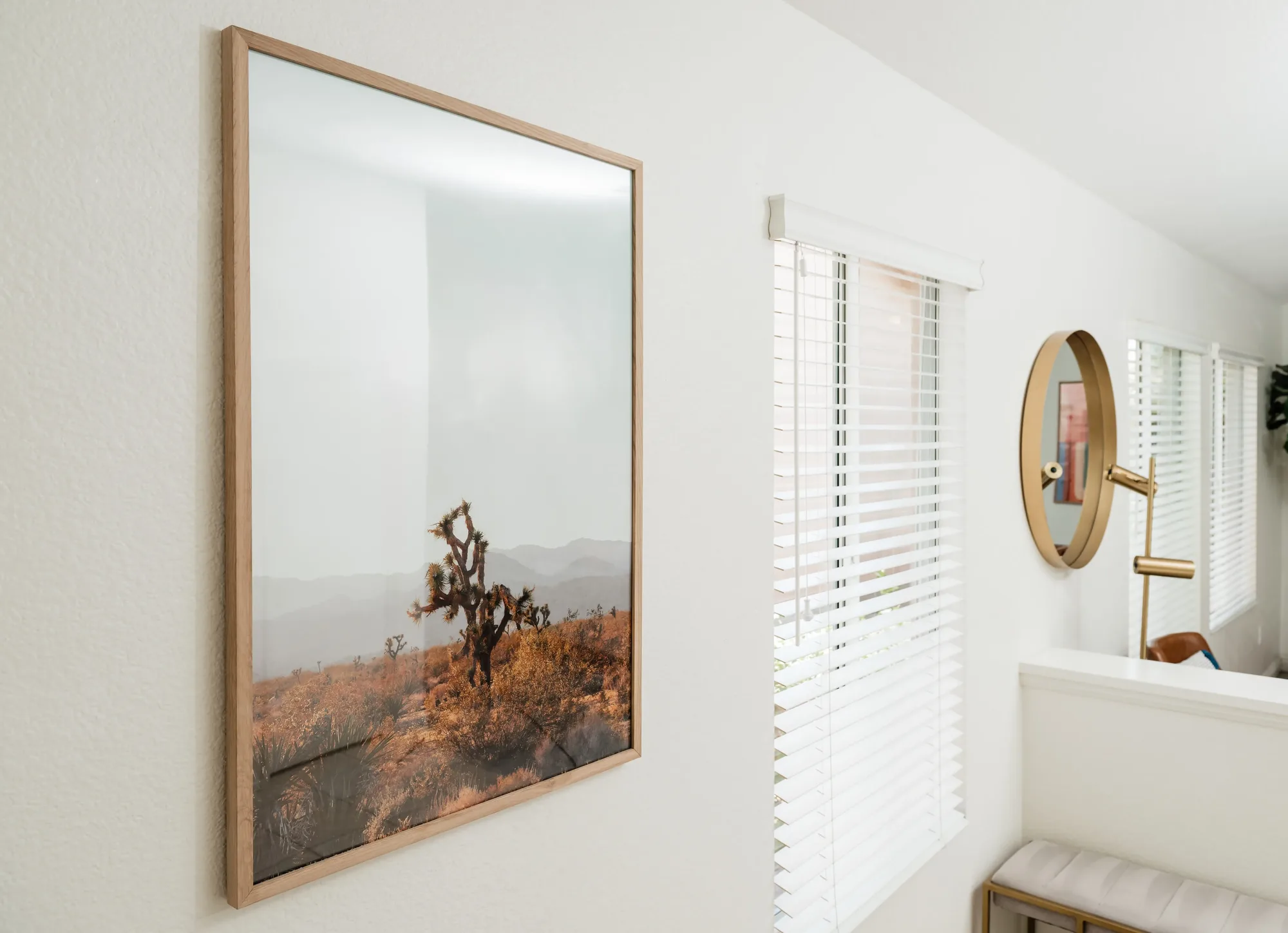 Cozy Cactus wall detail with Joshua Tree desert landscape print and gold round mirror