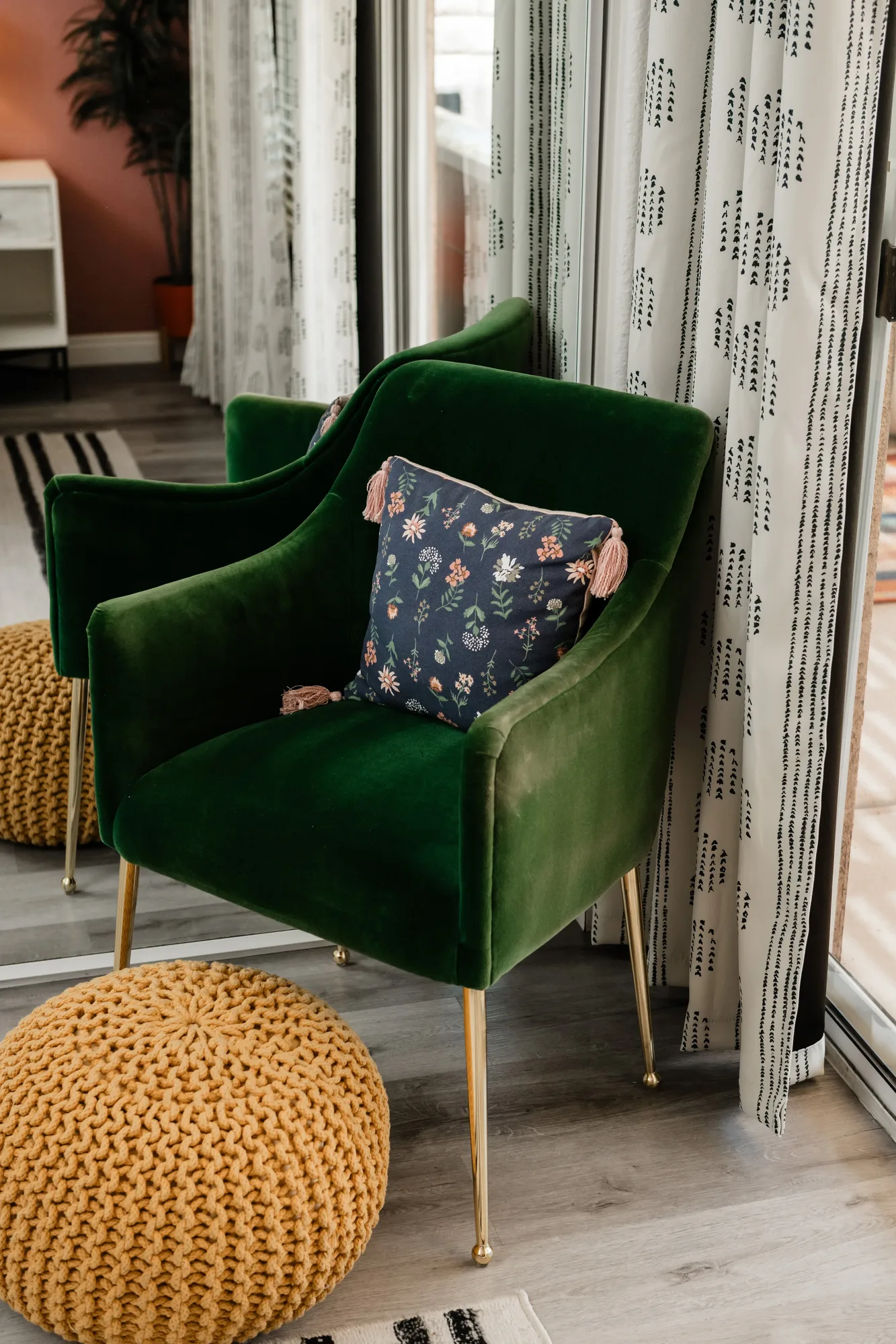 Cozy Cactus primary bedroom sitting area with two green velvet chairs, floral pillows, and mustard knit pouf