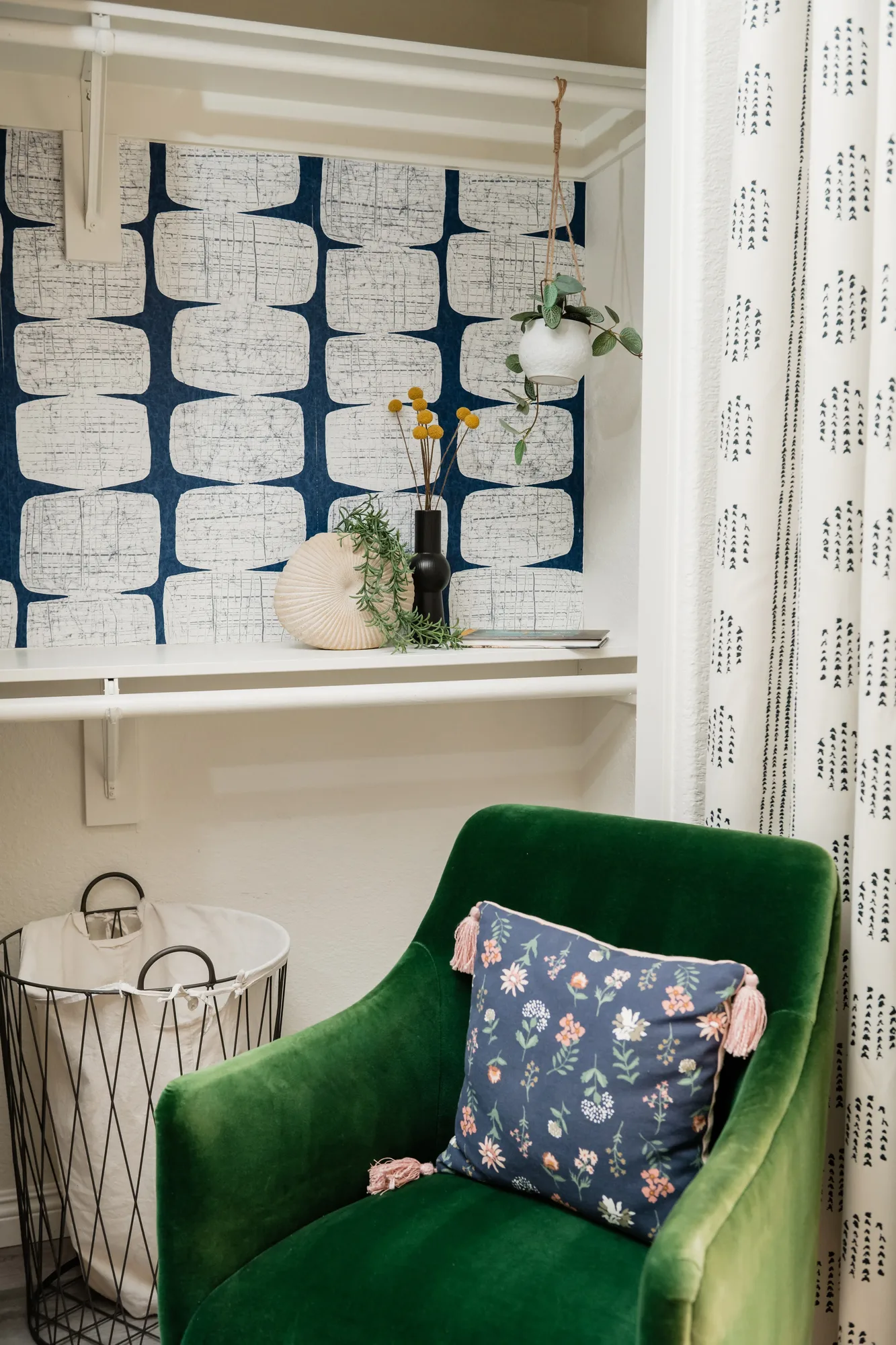 Green velvet chair detail with navy botanical graphic wallpaper and hanging plant in Cozy Cactus