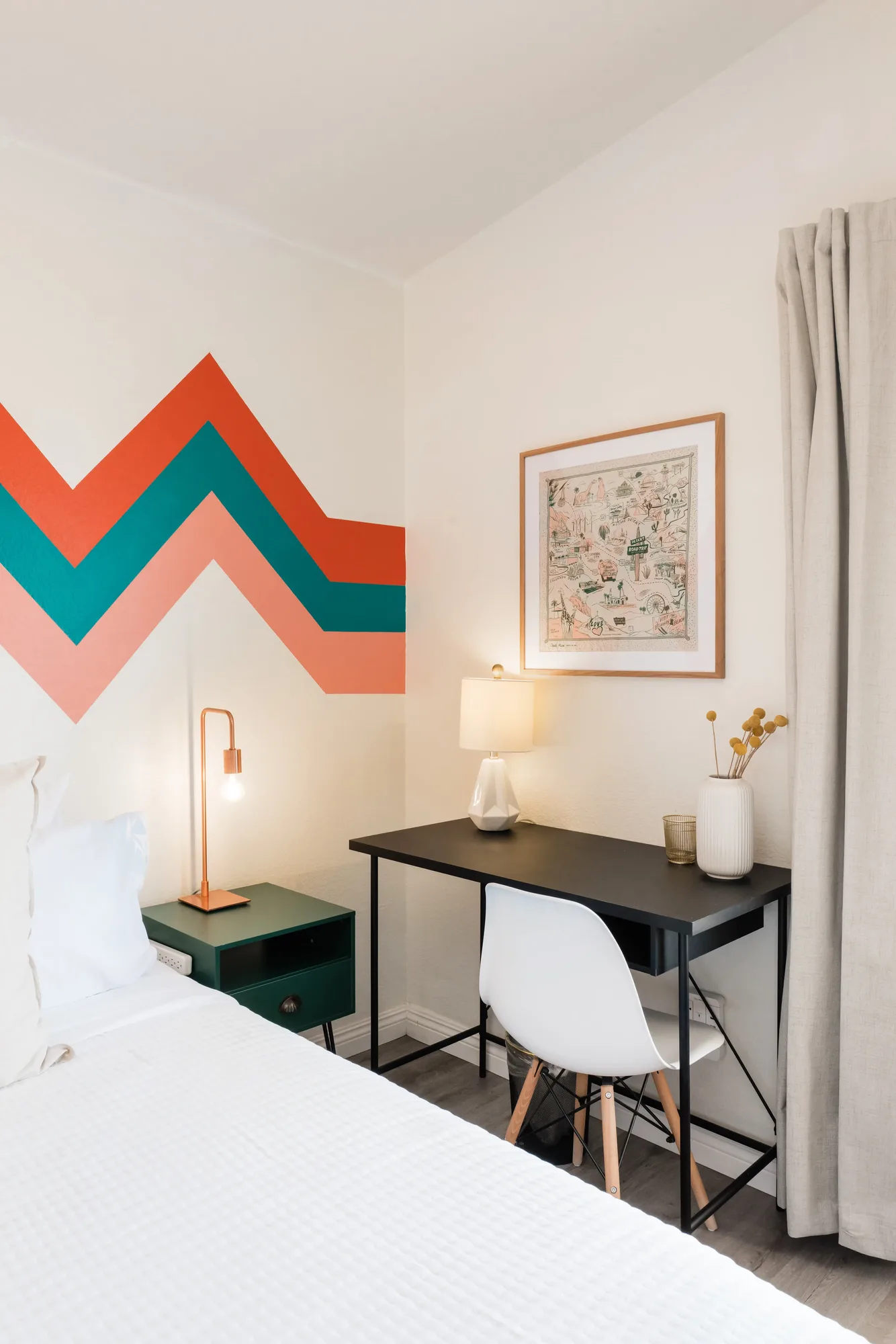 Cozy Cactus bunk bedroom with coral and teal chevron painted wall, dark green nightstand, white queen bed, and desk