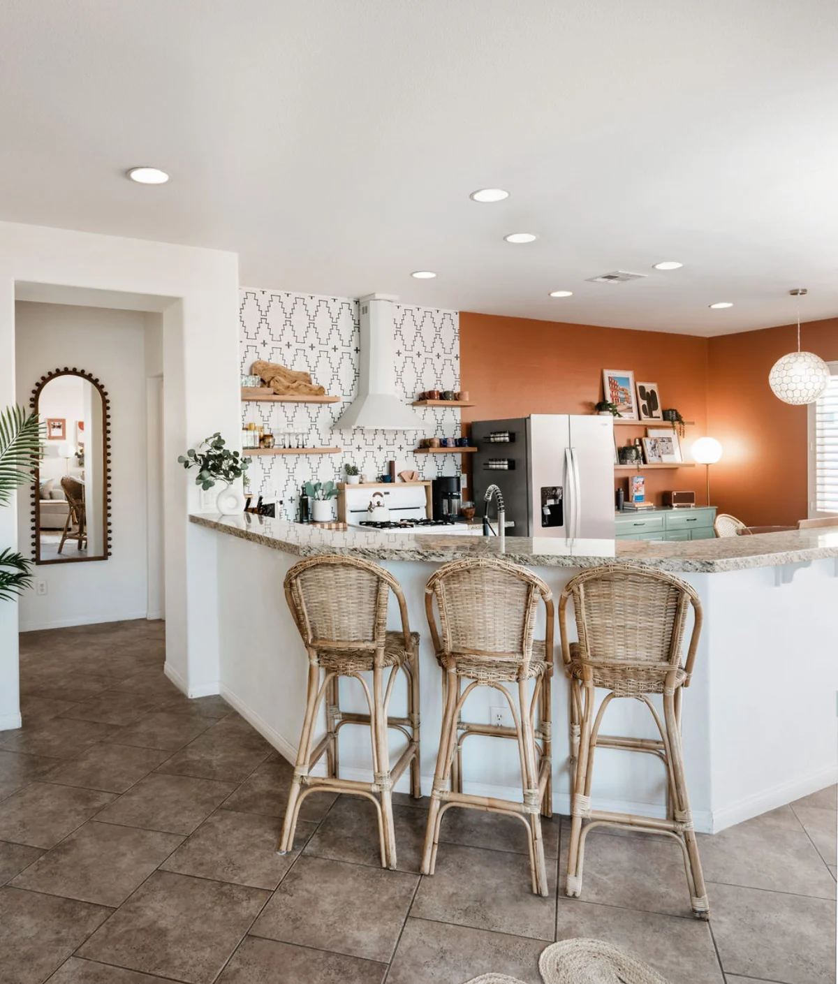 Terra Luz kitchen island with rattan bar stools viewed from living area showing terracotta wall and pendant light