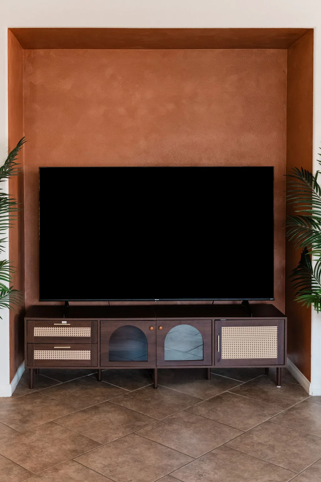 Terra Luz terracotta lime-wash TV niche with walnut credenza and tropical floor plants