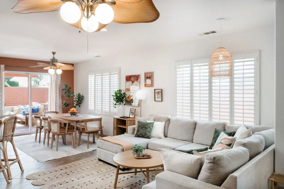 Terra Luz open living and dining area showing sectional sofa, round coffee table, eight-seat dining table, rattan pendant light, and ceiling fan