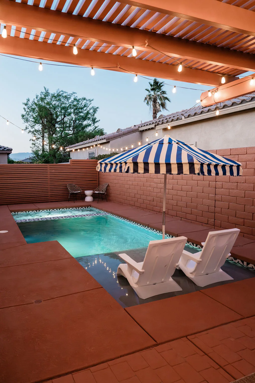 Terra Luz pool at twilight with string lights overhead and desert sky in Indio California