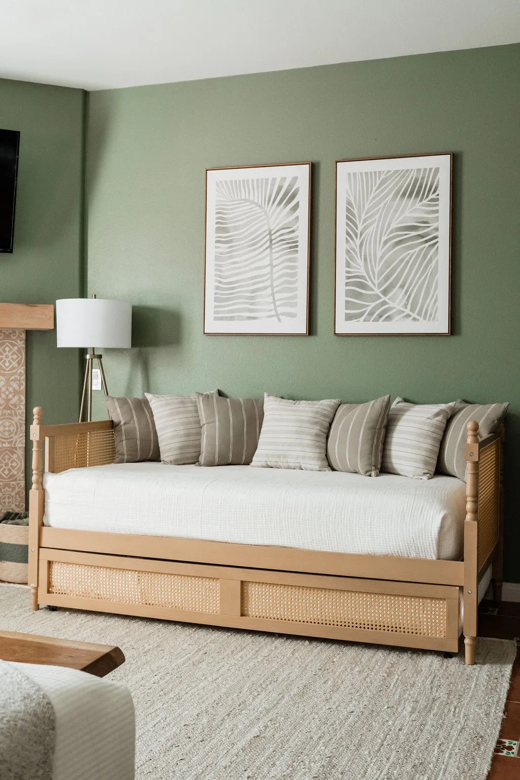 Terra Luz primary bedroom sitting area with cane daybed, palm frond prints, and sage green walls