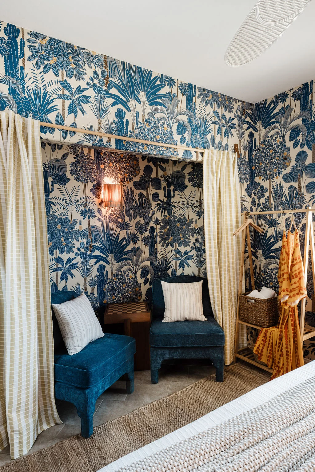 Terra Luz wallpaper bedroom seating nook with two blue velvet chairs and Rebel Wall tropical wallpaper floor to ceiling