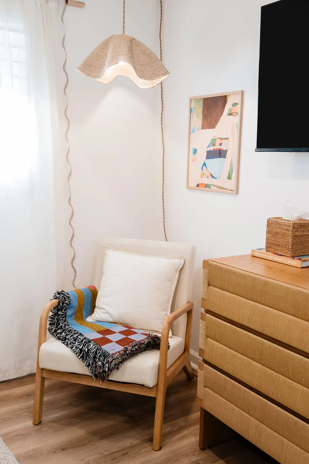 The Sundune Palm Springs primary bedroom corner with lounge chair, abstract art, and ribbed dresser