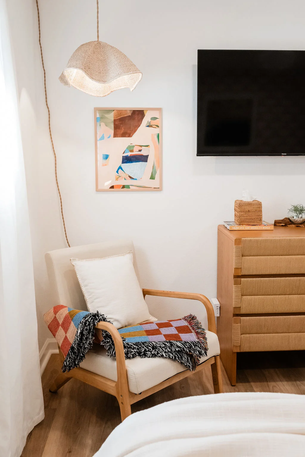 The Sundune Palm Springs primary bedroom corner with wavy pendant lamp, lounge chair, and checkerboard throw