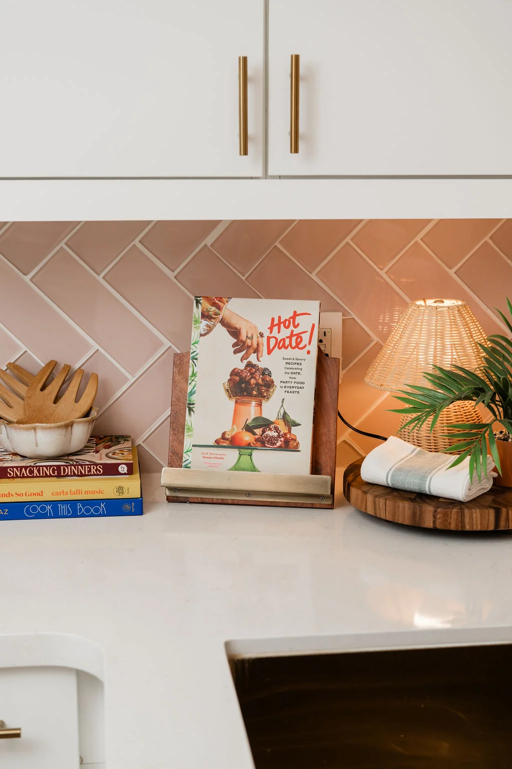 The Sundune Palm Springs kitchen counter with Hot Date cookbook and rattan lamp against pink tile