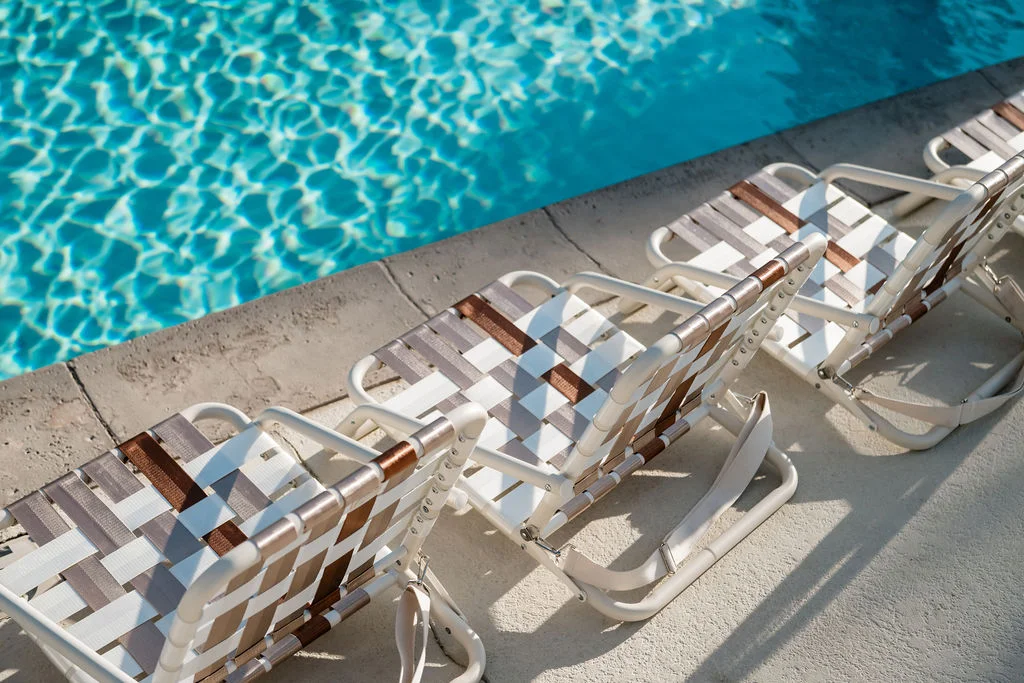 The Sundune Palm Springs community pool with vintage woven lounge chairs and clear water